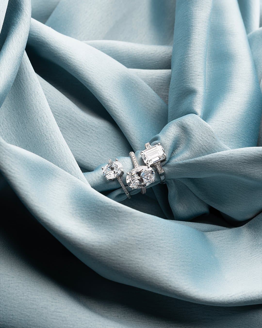 Diamond engagement rings nestled in folds of light-blue silk