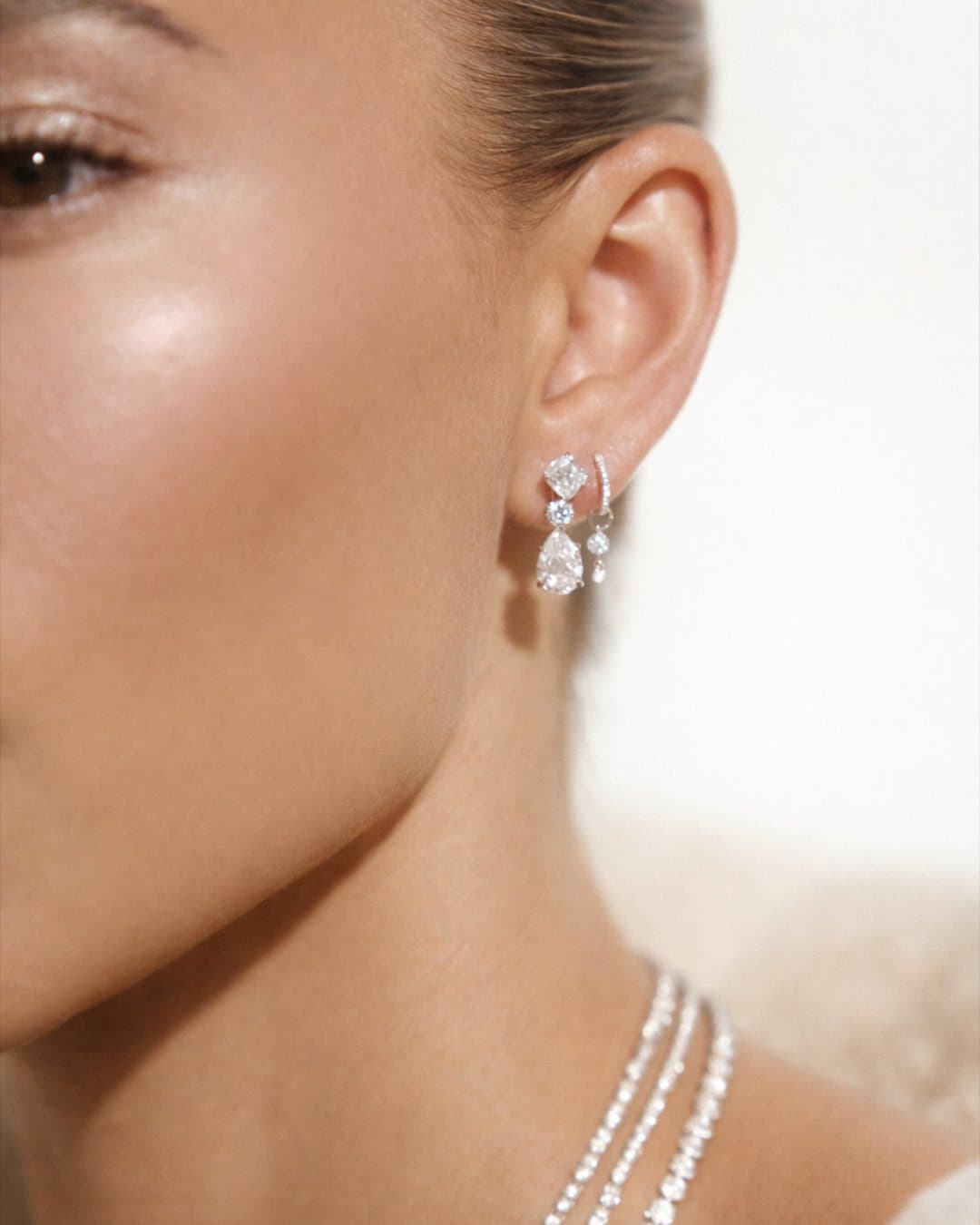 Model wearing diamond drop earrings and a layered diamond necklace